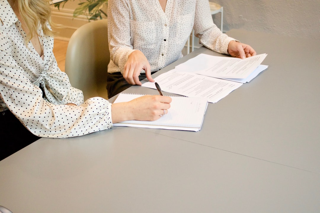 woman-signing-on-white-printer-paper-beside-woman-about-to-touch-the-documents-hjckknwcxxq